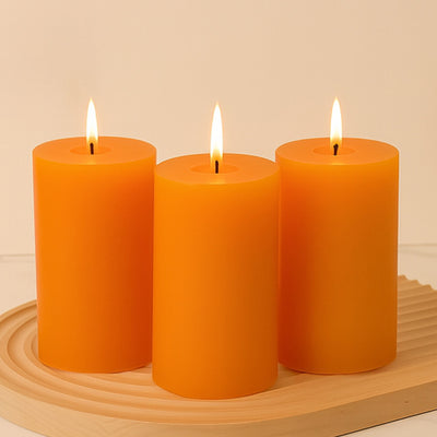 Three orange candles with flames on a wooden tray.