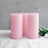 Pink frosted candles with greenery on a soft surface.
