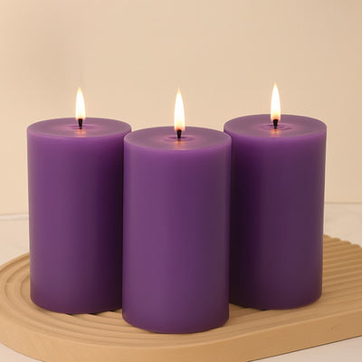 Three purple candles with flames on a wooden tray.