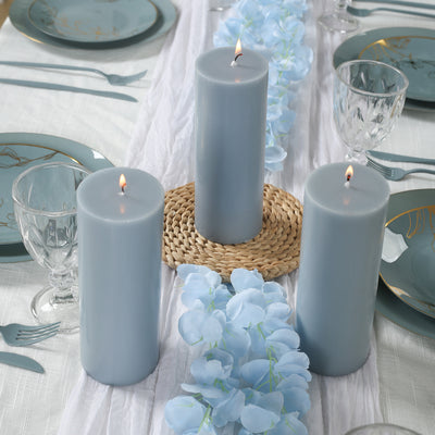 Three blue candles on a table with floral decor and elegant glassware.