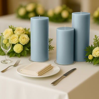 Blue pillar candles on a dining table with floral arrangements and tableware.