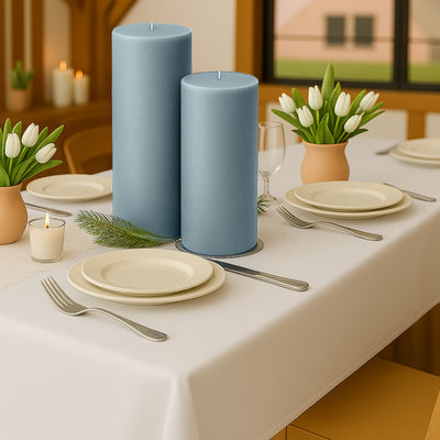 Blue pillar candles on a dining table with floral accents and dinnerware.