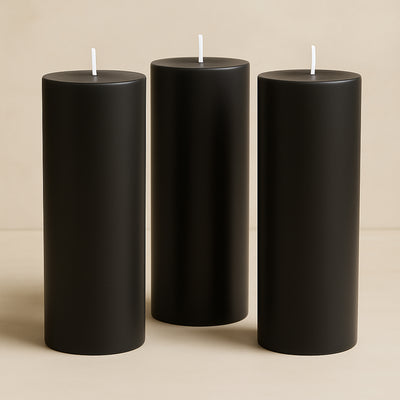 Set of three tall black candles on a neutral background.