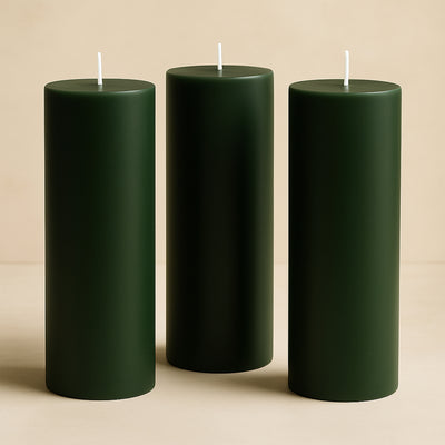 Green pillar candles in varying heights on a neutral background.