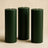 Green pillar candles in varying heights on a neutral background.