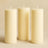 Three cream pillar candles on a neutral background.