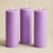 Three purple pillar candles on a beige background.