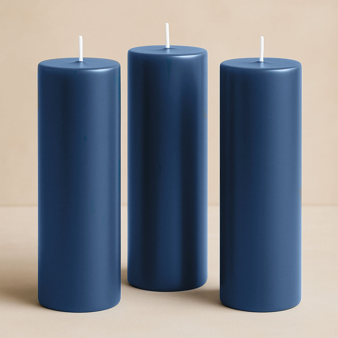 Set of three navy blue pillar candles on a beige background.