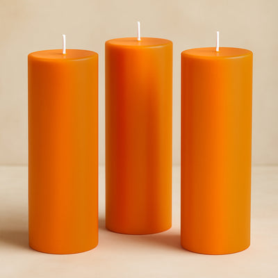 Set of three orange pillar candles in varying heights.