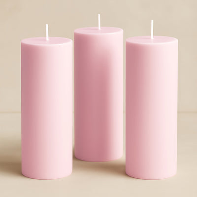 Three pink pillar candles in varying heights against a soft beige background.