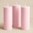 Three pink pillar candles in varying heights against a soft beige background.