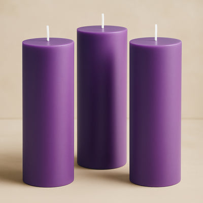 Purple pillar candles in varying heights against a soft beige backdrop.