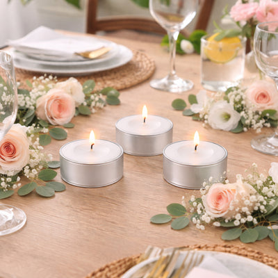 Silver tin candles on a beautifully set dining table with floral accents.