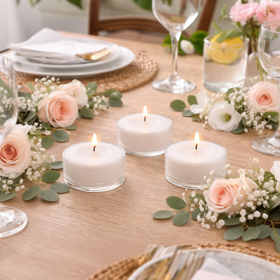 Three white candles on a beautifully arranged dining table with floral accents.