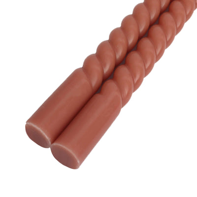 Twisted candles in warm terracotta color, studio isolation shot