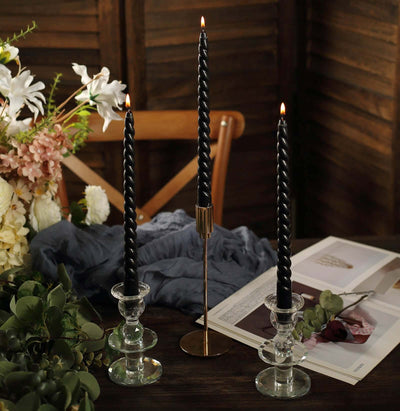 Elegant black twisted candles in glass holders on a rustic table setting.