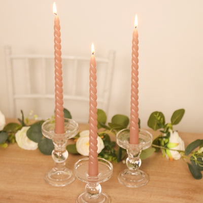 Three twisted candles in glass holders, lit and elegantly displayed.