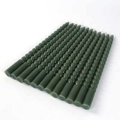 Green decorative taper candles arranged neatly on a white background