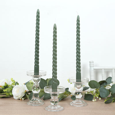 Set of three green twisted candles in clear glass holders.