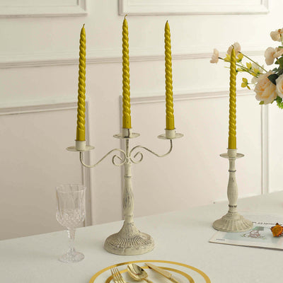 Elegant candle holder with twisted yellow candles and decorative glassware.