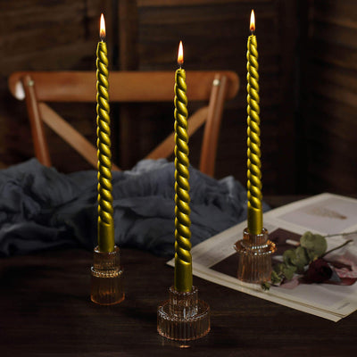 Twisted green candles in glass holders on a wooden table