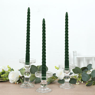 Green twisted candles in clear glass holders with floral accents.