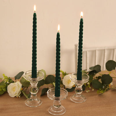 Green twisted candles in glass holders with floral accents.