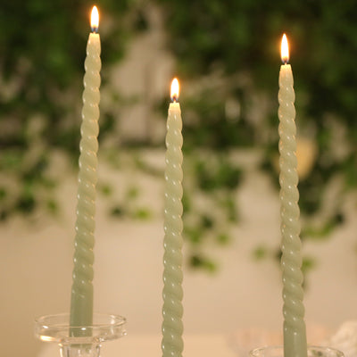 Three spiral candles lit, creating a warm ambiance against a blurred green background.