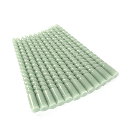 Green twisted taper candles arranged in a neat row.