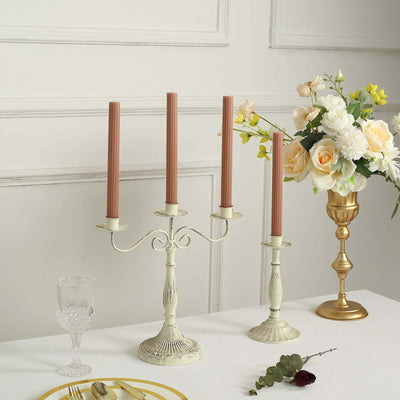 Elegant candle holder with four candles, styled with flowers and glassware in a table setting.