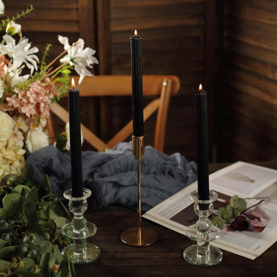 Elegant black taper candles in crystal holders on a rustic table setting.