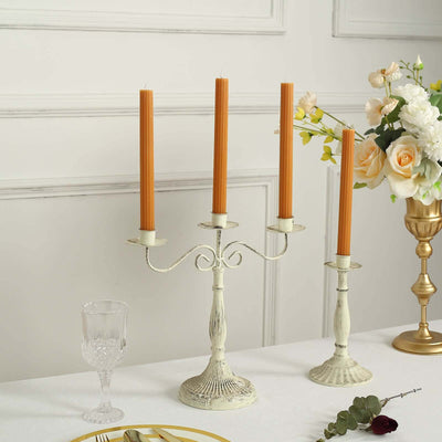 Elegant vintage candle holder with four orange candles and decorative accents.