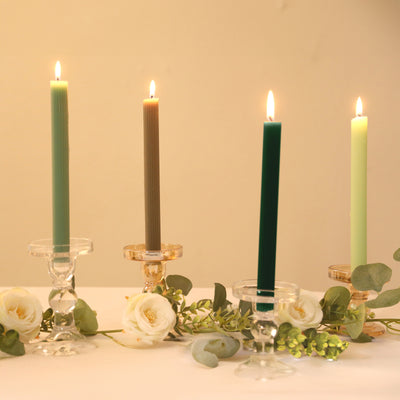 Colorful candles in elegant holders with flowers and greenery