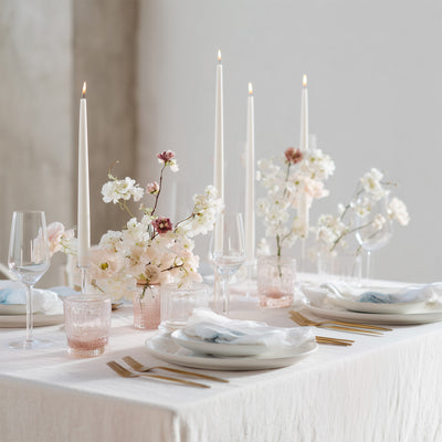 Elegant dining table set with flowers, candles, and glassware.