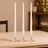 Three elegant glass candle holders with white taper candles.