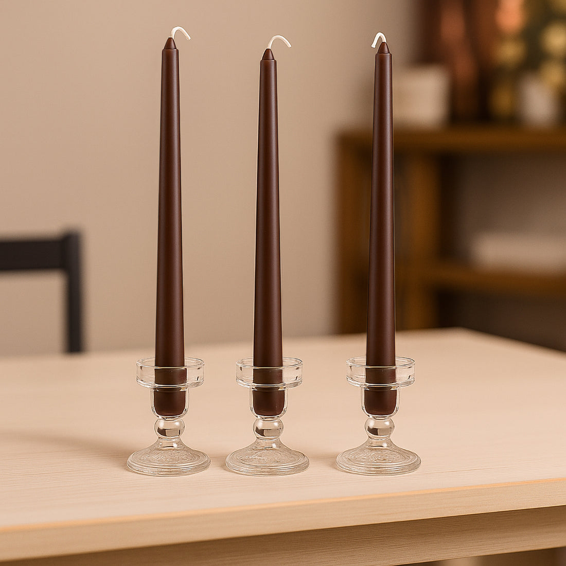 Brown taper candles in glass holders on a wooden table.