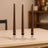 Brown taper candles in glass holders on a wooden table.