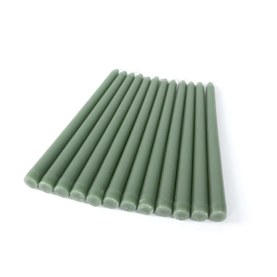 Green taper candles arranged in a neat row on a white background.