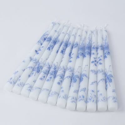 Set of decorative blue and white floral candles on a plain background