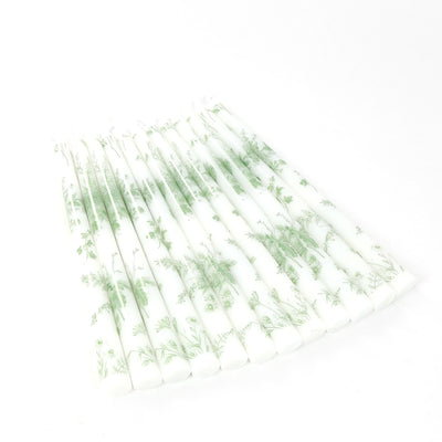 Decorative green floral patterned candles on a white background.