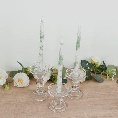 Three elegant glass candle holders with green decorative candles.