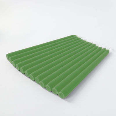 Green taper candles arranged in a neat row on a white background.