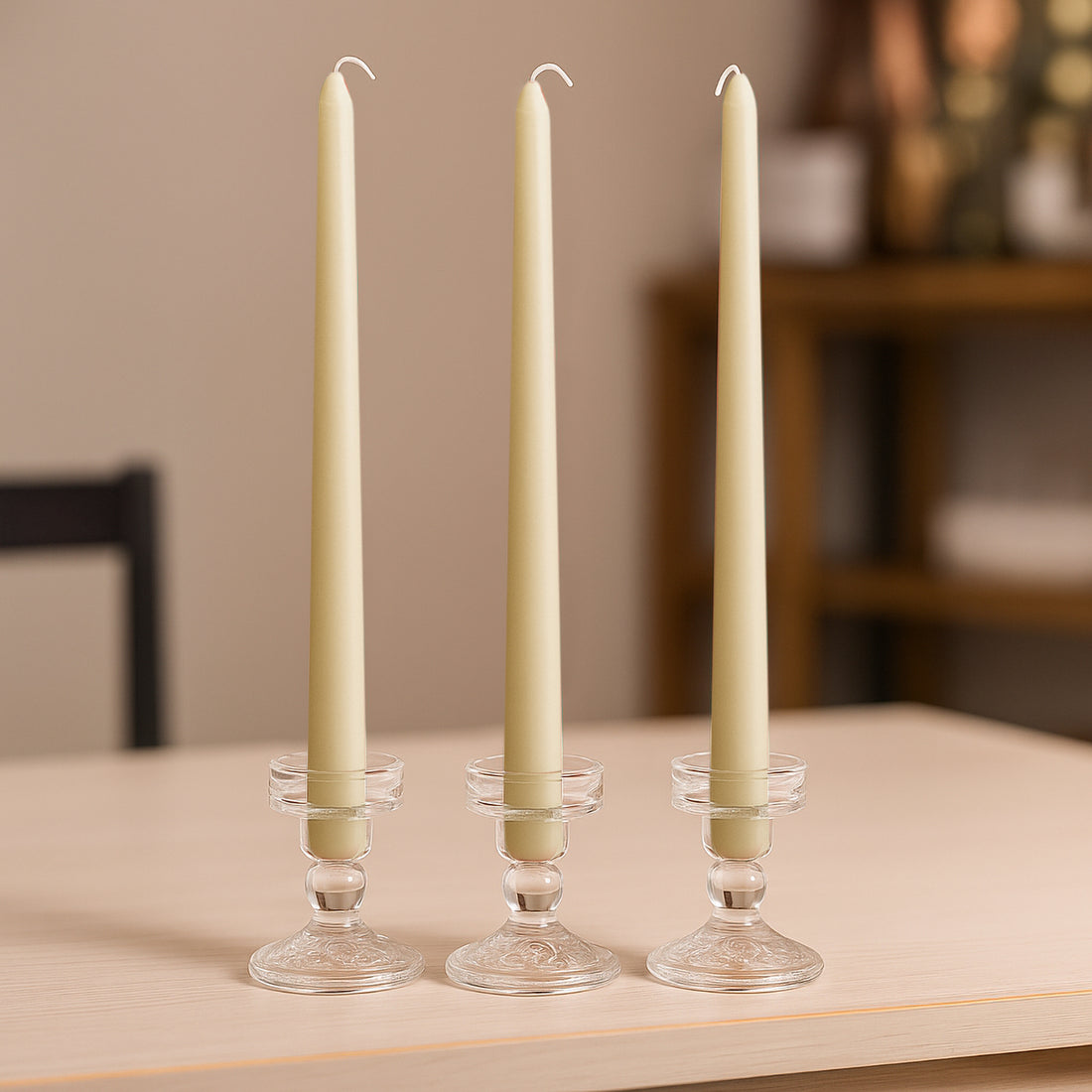 Elegant cream taper candles in crystal holders on a wooden table.