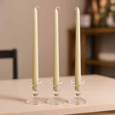 Elegant cream taper candles in crystal holders on a wooden table.