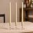 Elegant cream taper candles in crystal holders on a wooden table.