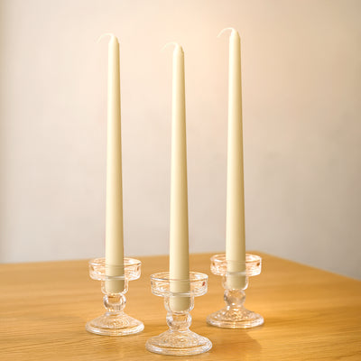 Elegant cream candles in crystal holders on a wooden table.