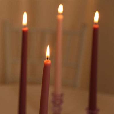 Colorful taper candles with flickering flames in a soft ambiance.