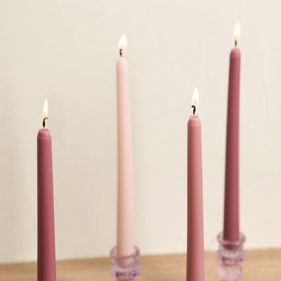 Set of four decorative tapered candles in shades of pink and purple.
