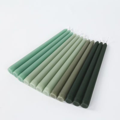 Green taper candles in various shades arranged neatly.