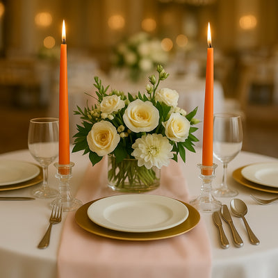 Elegant table setting with orange candles and floral centerpiece.